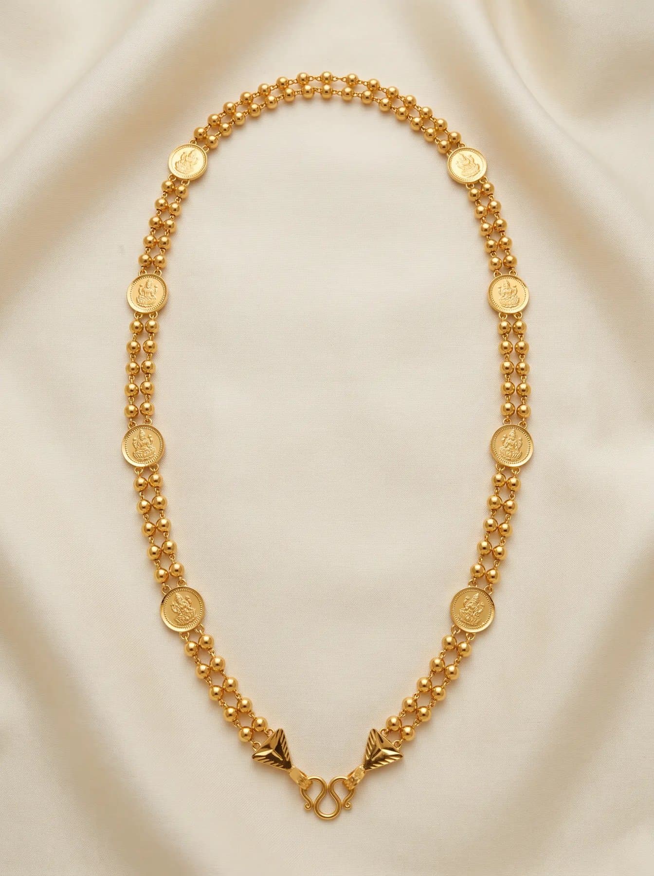 Long double-strand gold bead mala set with Lakshmi coins, coiled on ivory silk